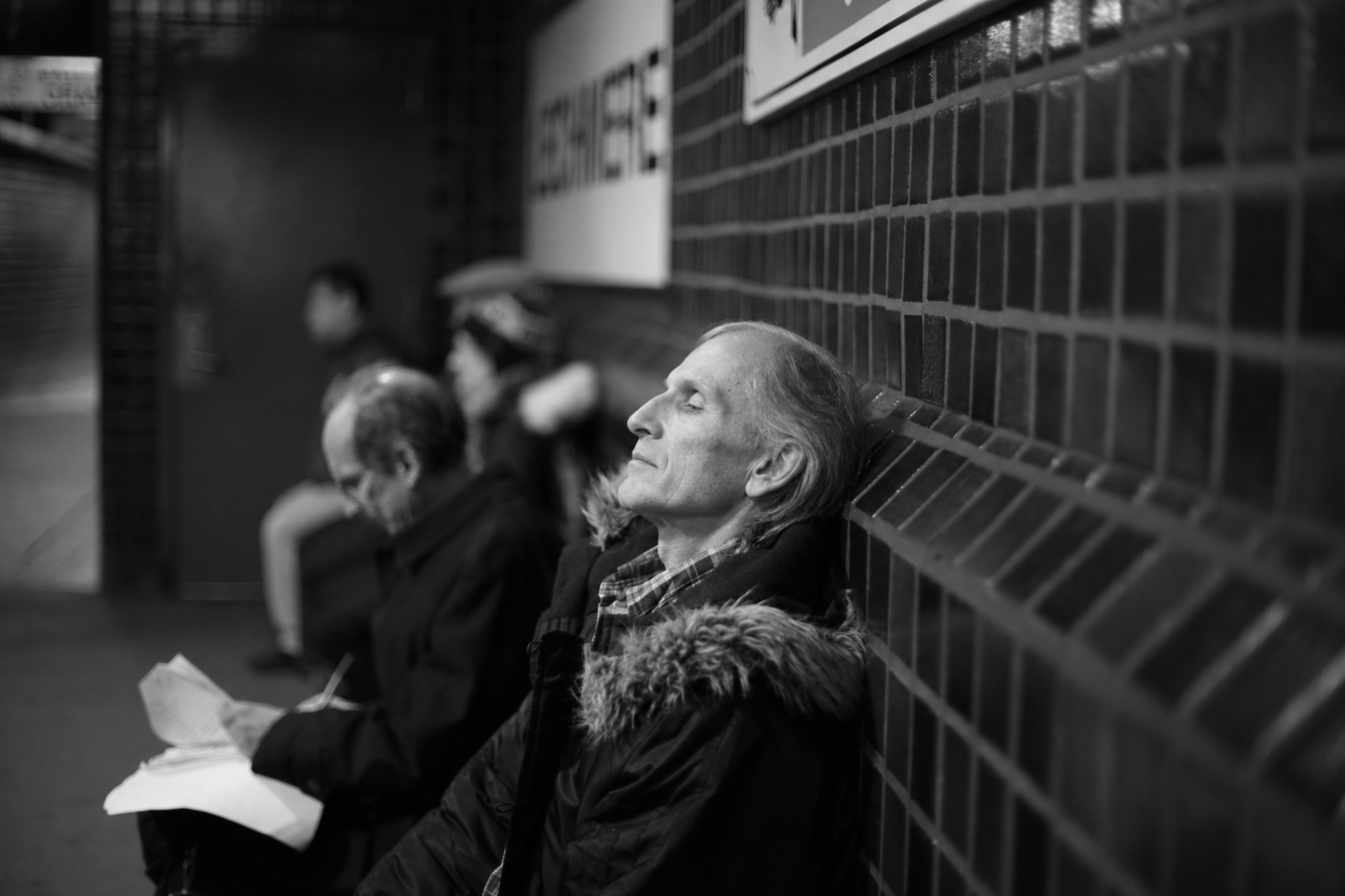 Silas Crowe resting against a tiled wall in a subway station