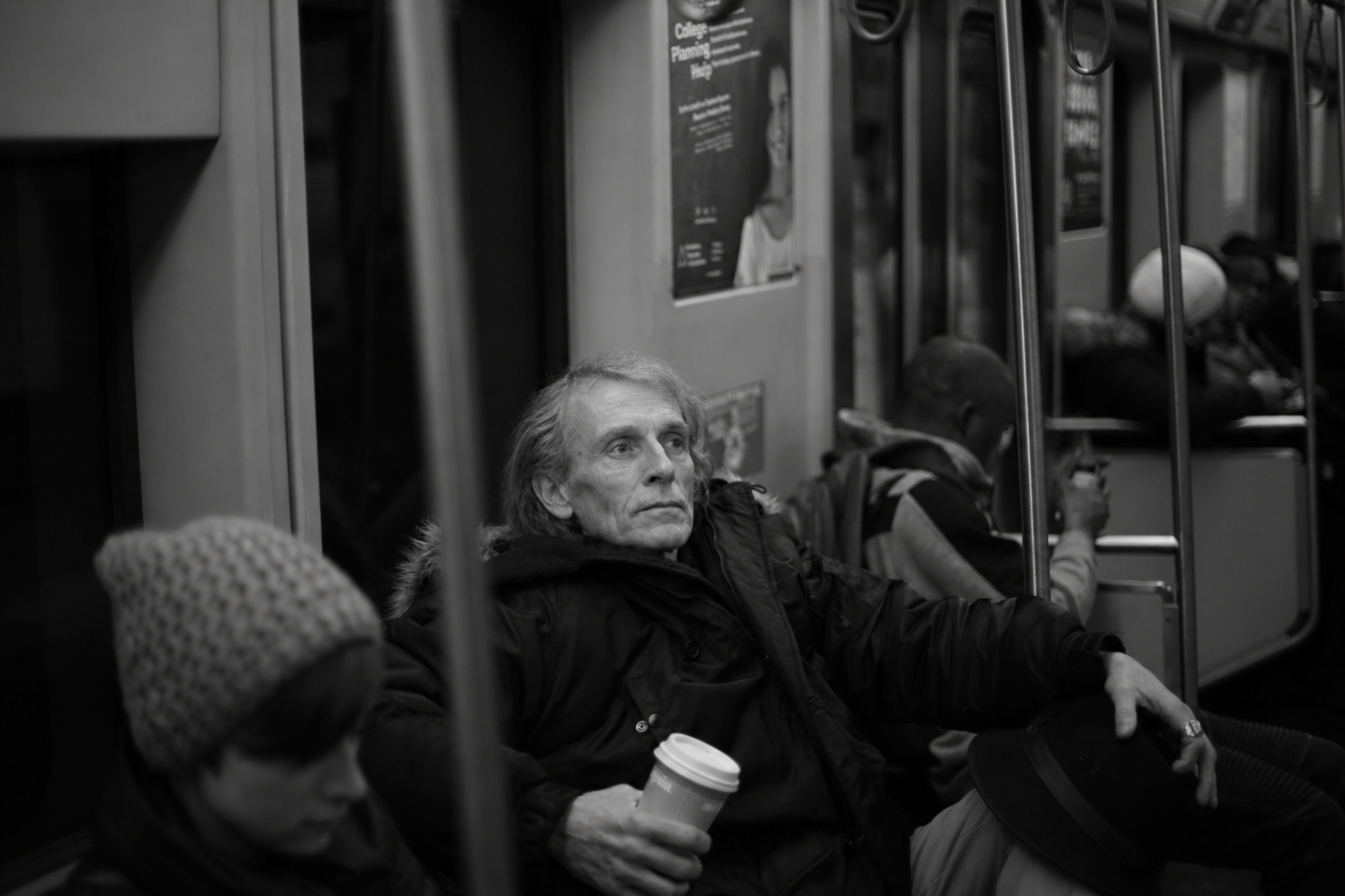 Silas Crowe on a subway train holding a coffee cup and hat